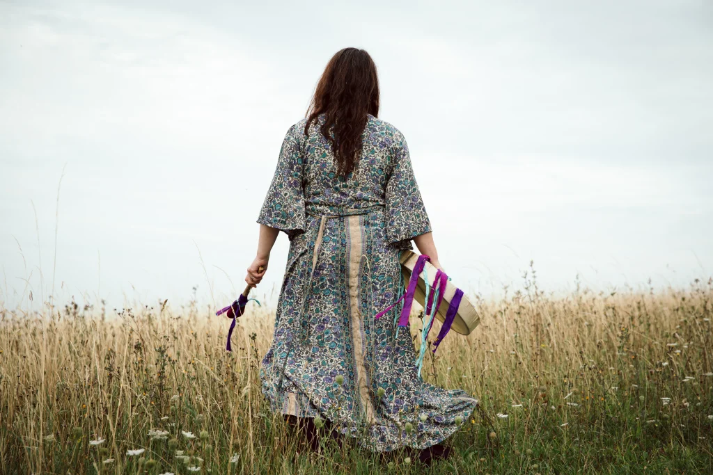 Sophie messager standing in a field looking away from the camera towards the horizon with open arms